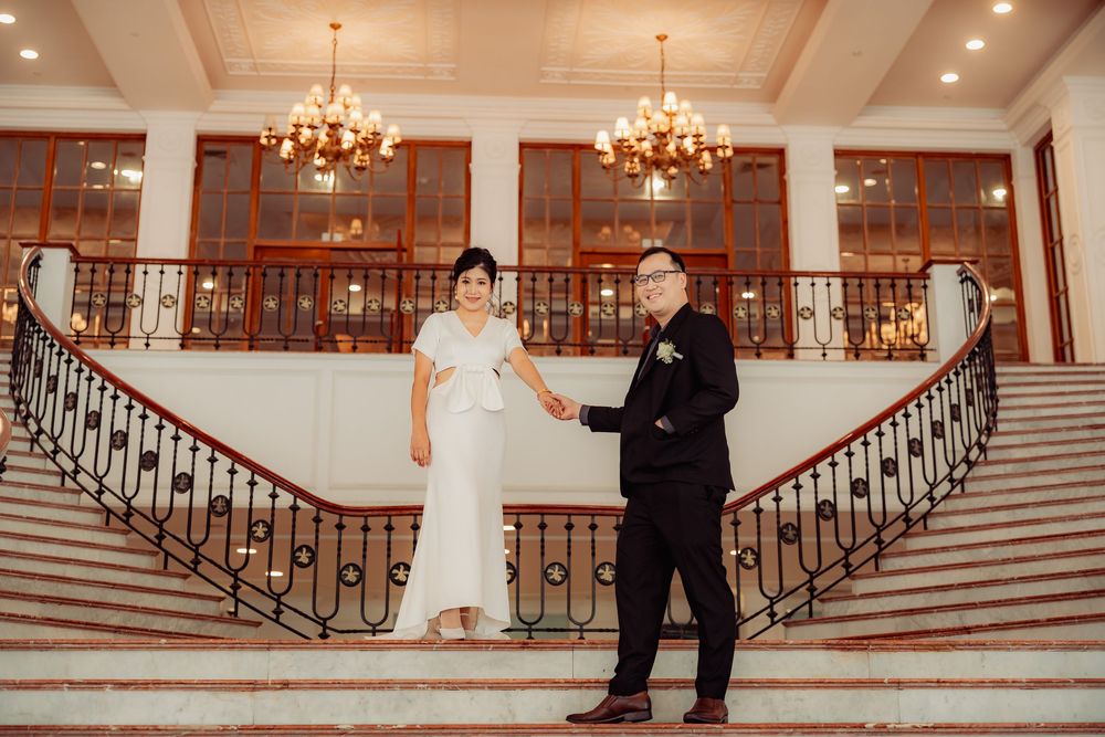 Elegant wedding ceremony scene with grand staircase and chandeliers in luxurious venue.