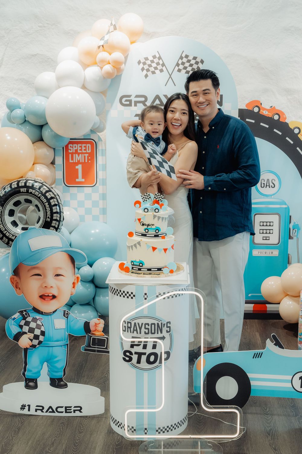 First birthday celebration with racing car theme decorations and blue balloon arrangements.