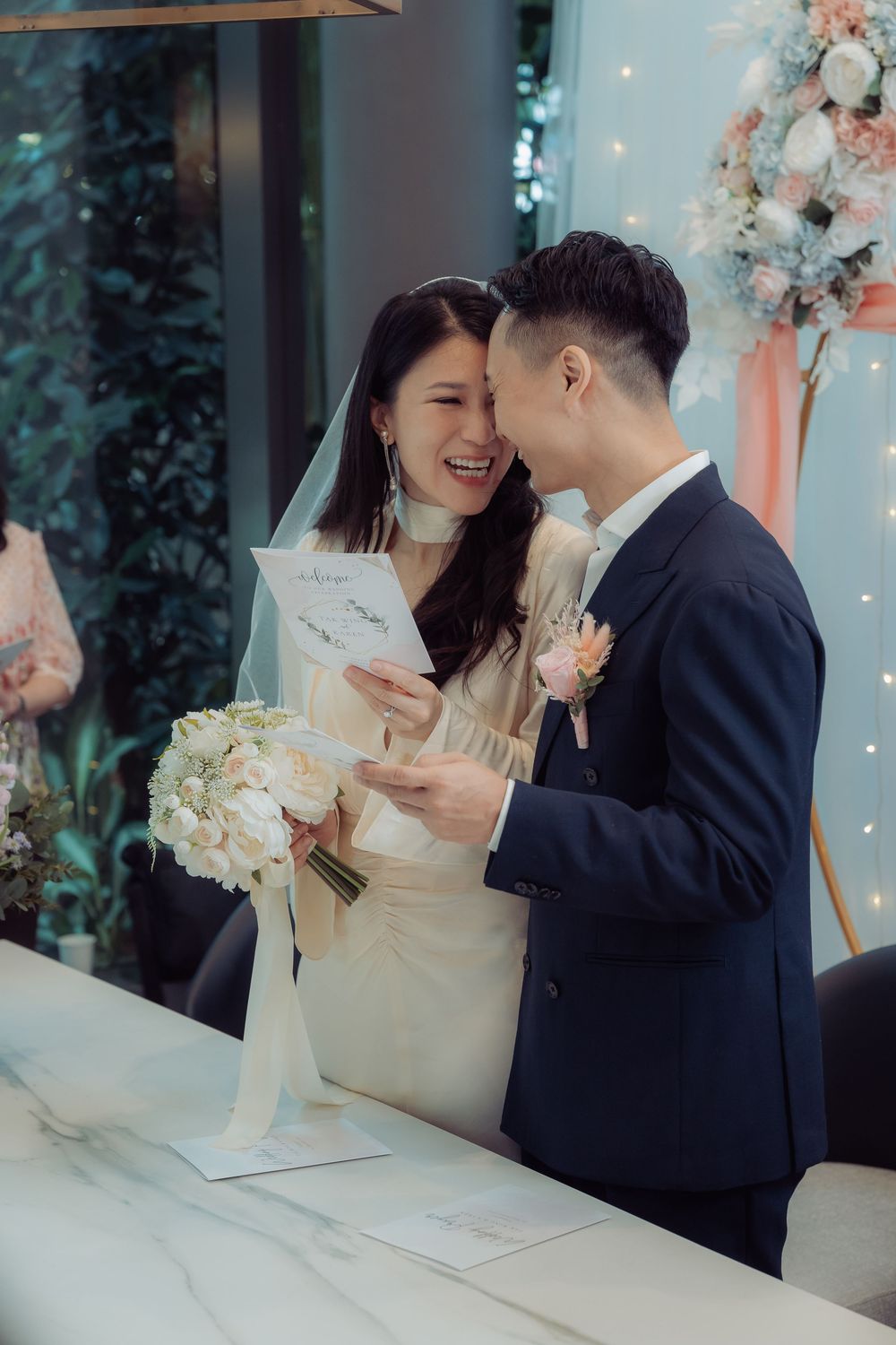 Wedding couple sharing joyful moments at a decorated table with floral arrangements.