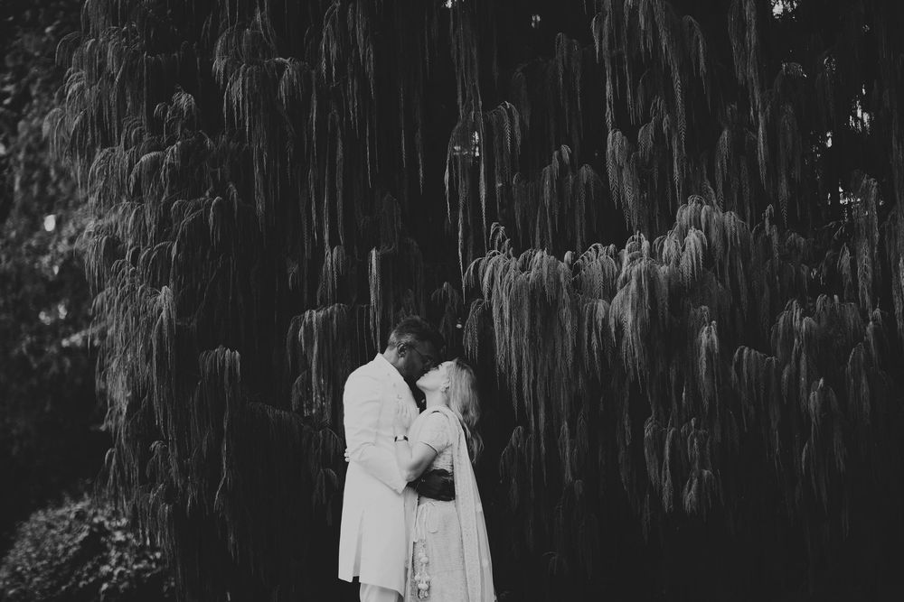 Romantic black and white wedding portrait under hanging willow branches.