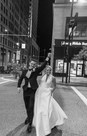 Wedding couple dancing and celebrating on a city street at night in black and white.