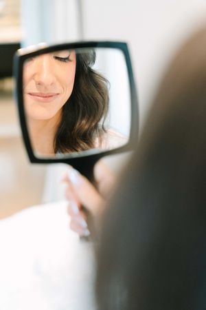 Close-up shot of a woman's smile and reflection in a mirror with soft focus.