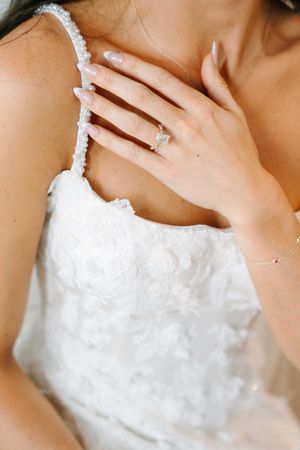 Close-up details of an elegant white wedding dress with delicate beading and lace trim.