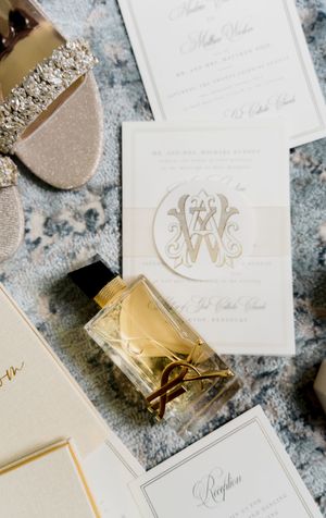 Elegant wedding invitations and stationery with gold monogram details and luxurious white paper displayed on textured surface.