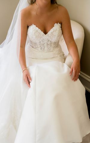 Close-up details of a white lace wedding dress with a sweetheart neckline and flowing fabric.