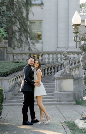 Romantic proposal moment on elegant stone steps with ornate railings and lamp posts.