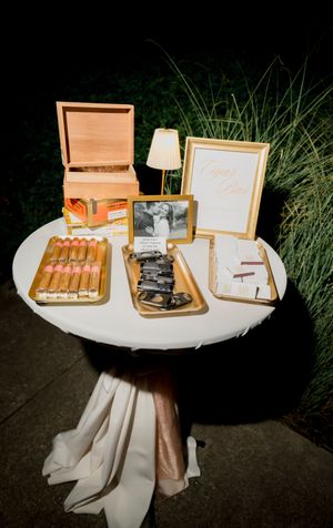 Wooden cigar boxes and event accessories arranged on a white tablecloth at an outdoor evening gathering.