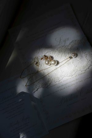 Pearl earrings and jewelry photographed in dramatic lighting on white paper.
