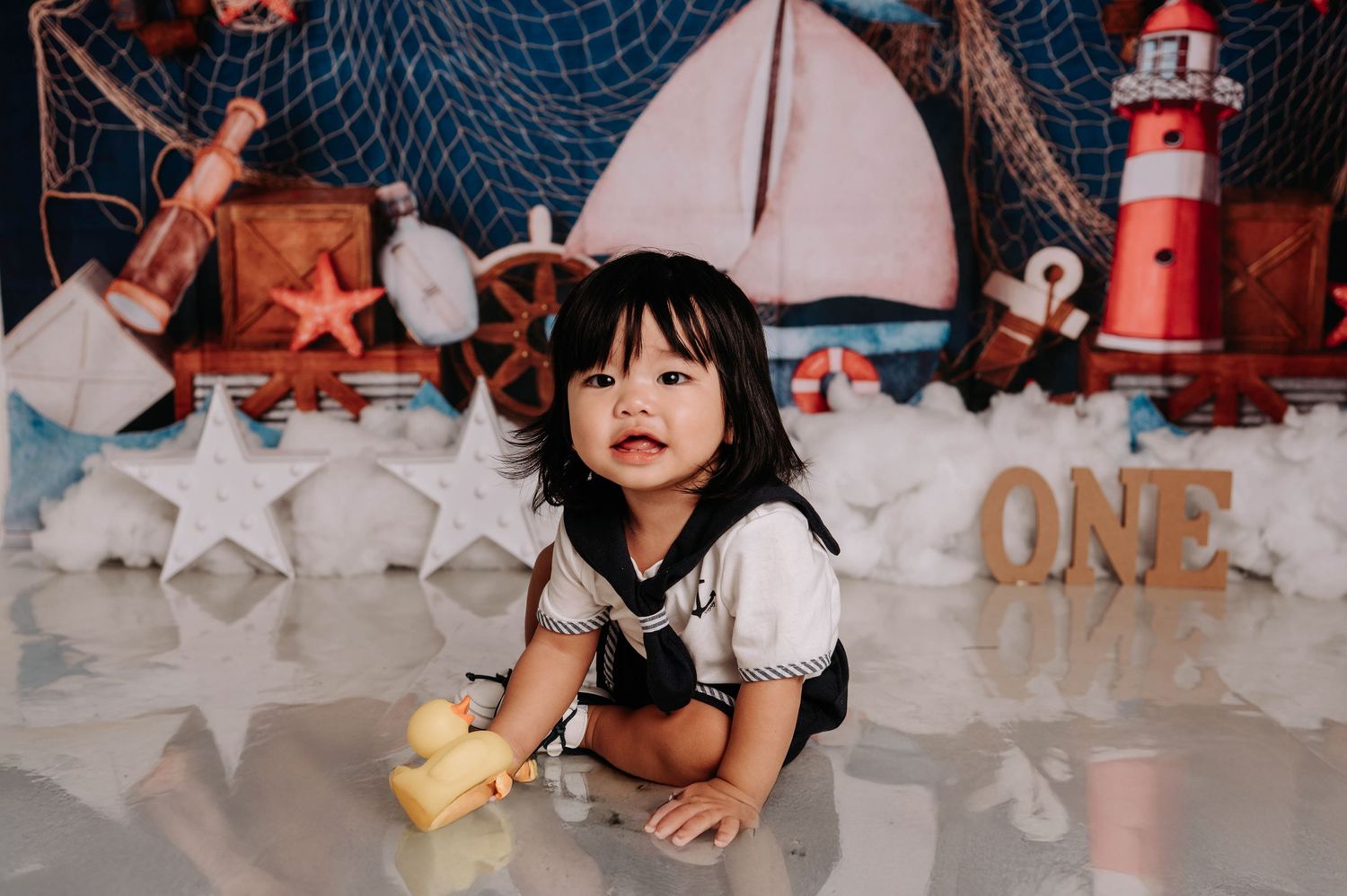 A nautical themed first birthday party setup with red and white decorations, lighthouse props, and spider web details.