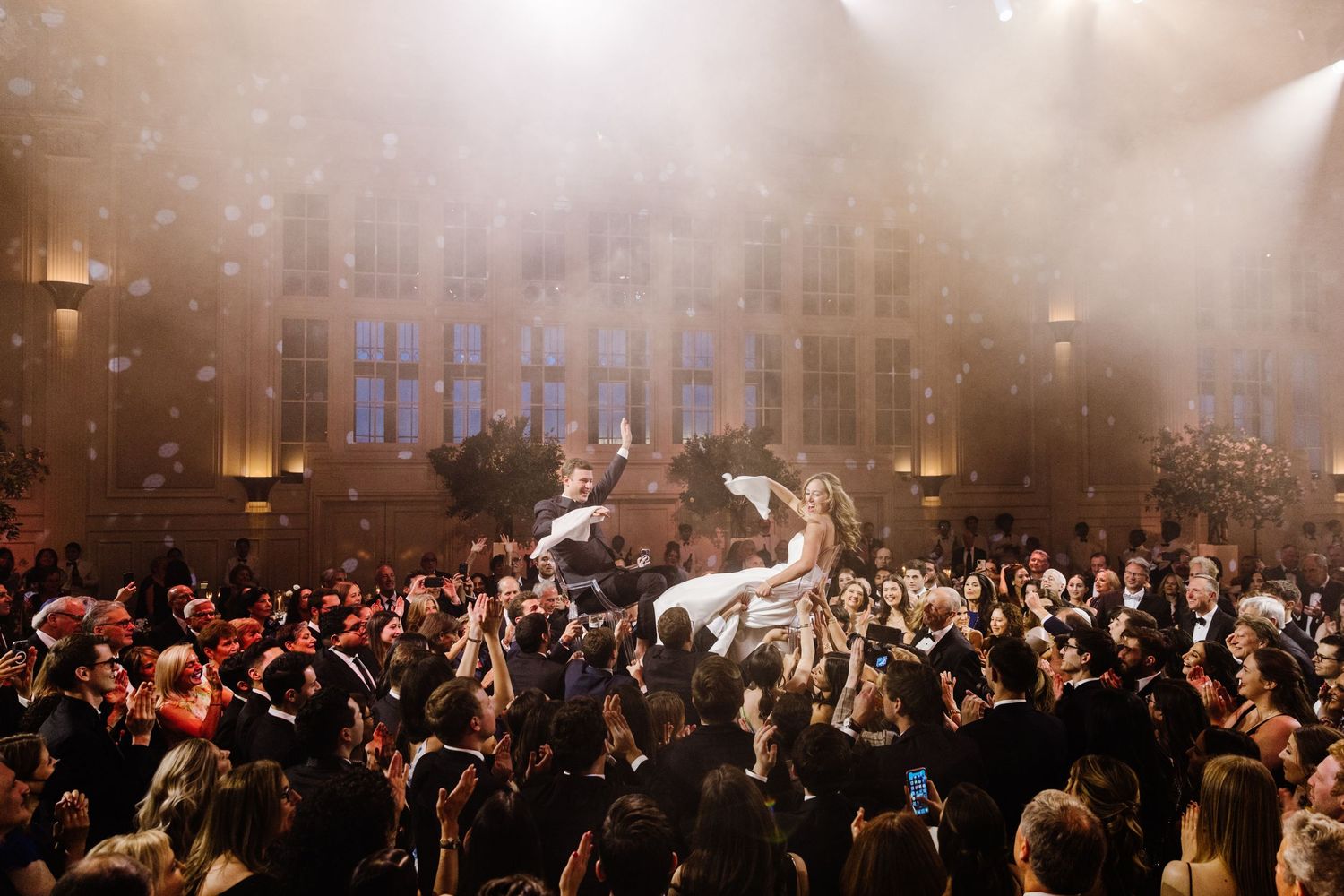 Concert crowd cheering in a dark venue with atmospheric fog and stage lighting creating a dramatic atmosphere.