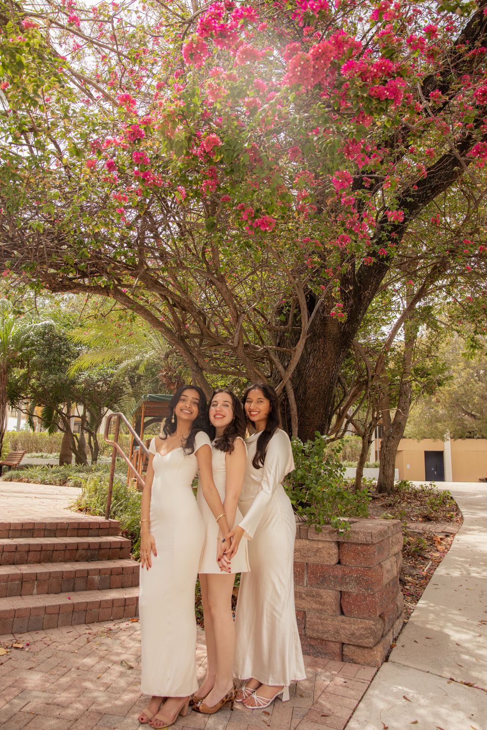 Group photo session under blooming pink bougainvillea archways in a garden setting.