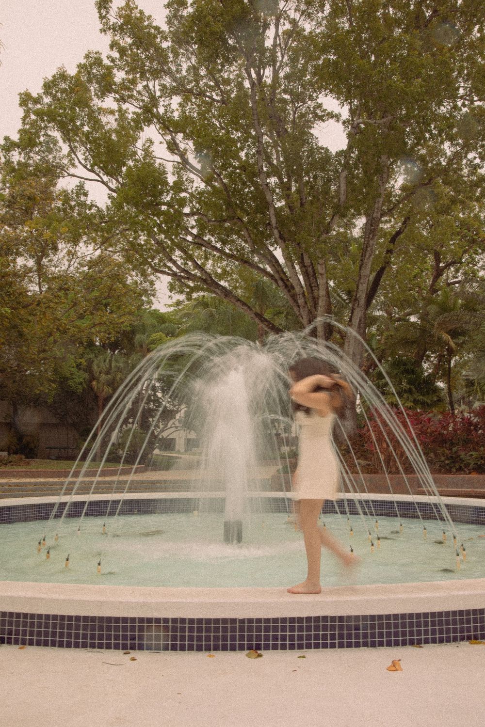 Artistic motion blur photos of dancing in a fountain with water sprays.