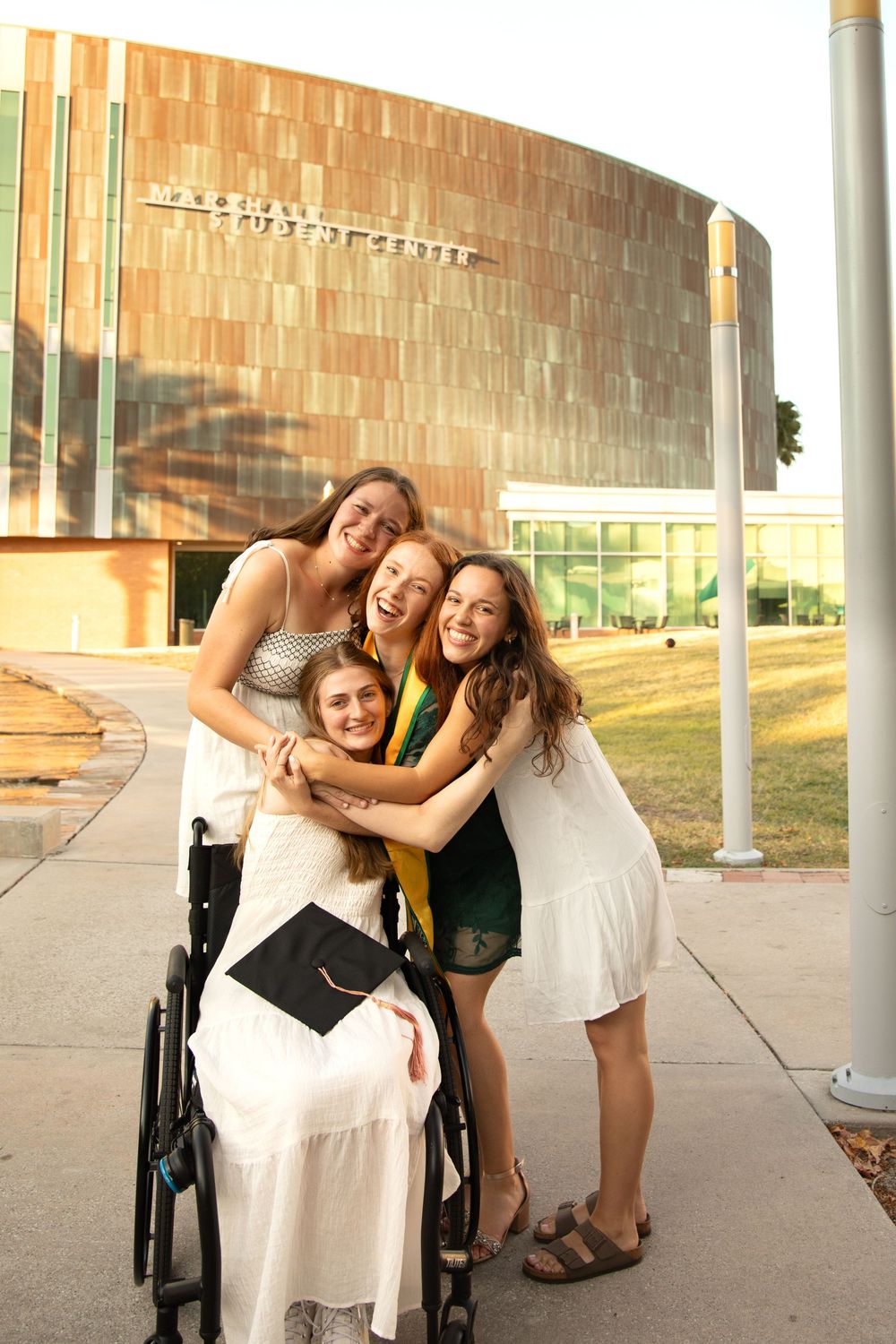 Friends pose playfully together outside a modern building with curved brick walls.