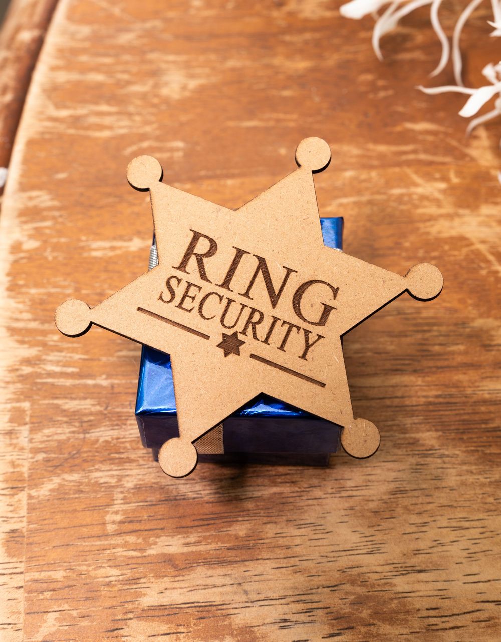 An image of a wooden star-shaped badge with the text 'RING SECURITY' printed on it.