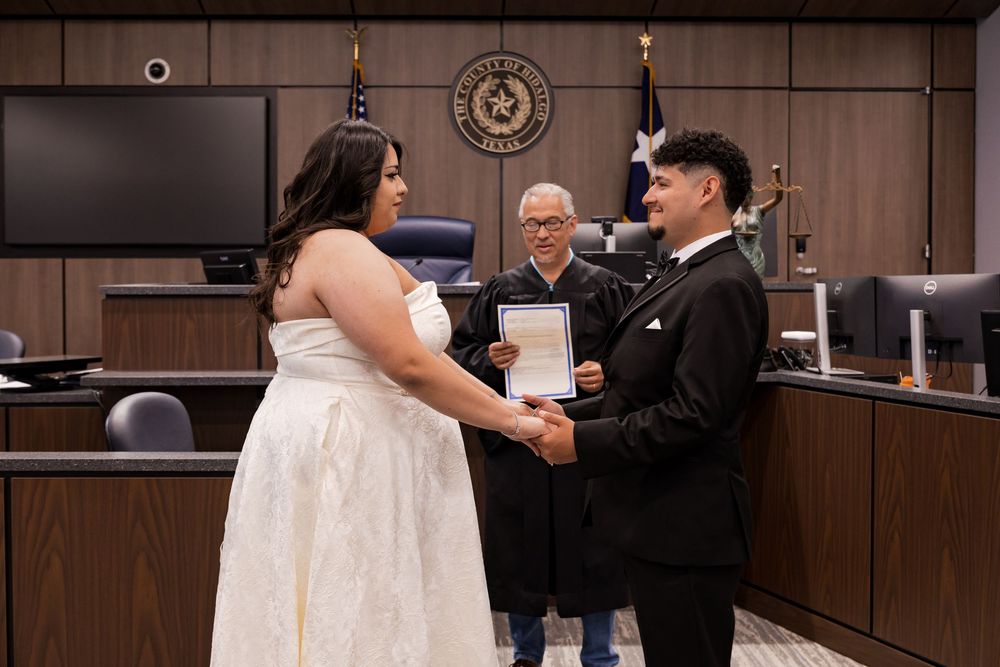 Couple exchanging vows at a Texas courthouse wedding ceremony with an officiant holding documents.
