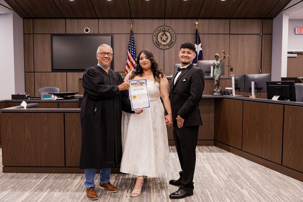 Couple posing with judge holding marriage certificate in Texas courthouse after civil wedding ceremony.