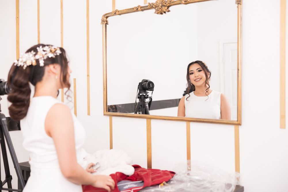 Elegant bride in white gown poses gracefully in a studio with peach and white striped walls.