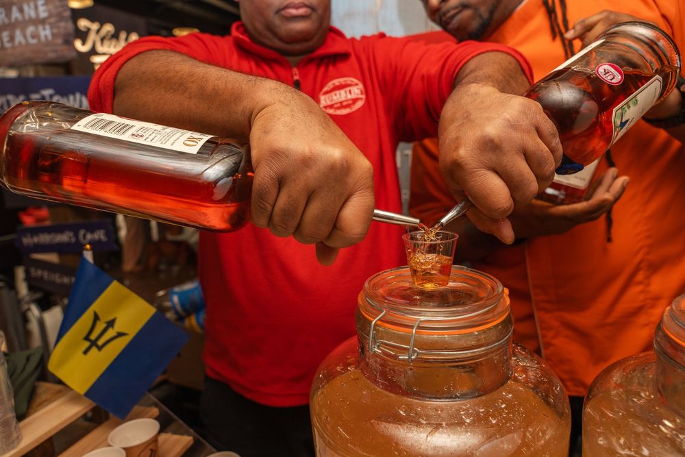 Staff members pouring drinks into containers at a beverage service counter.