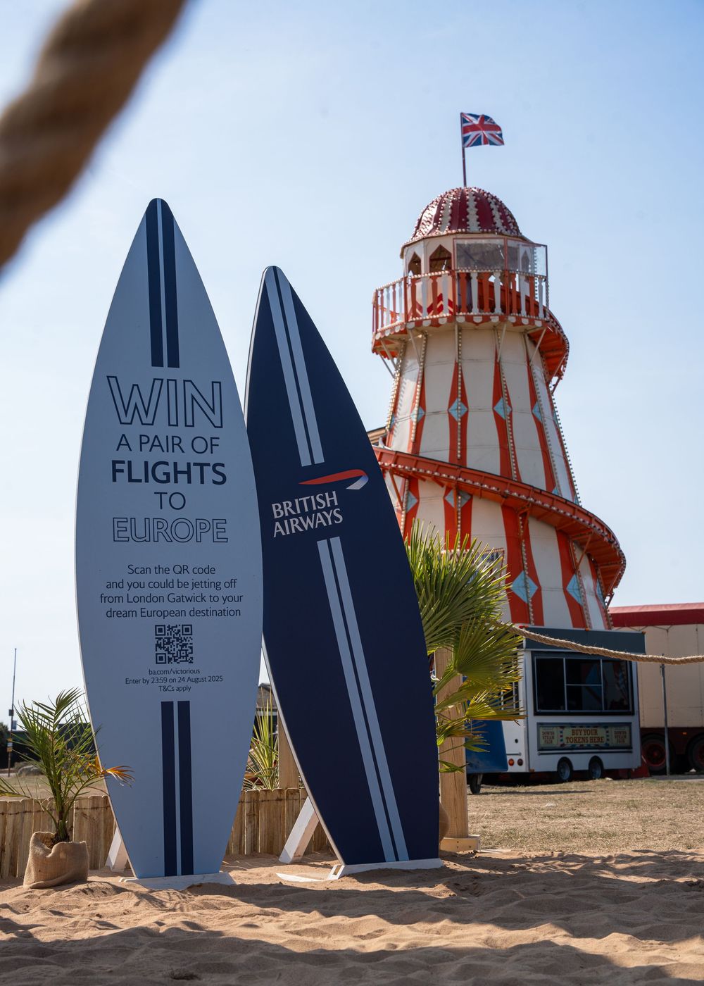 Large decorative surfboard displays with British Airways branding near a lighthouse structure.
