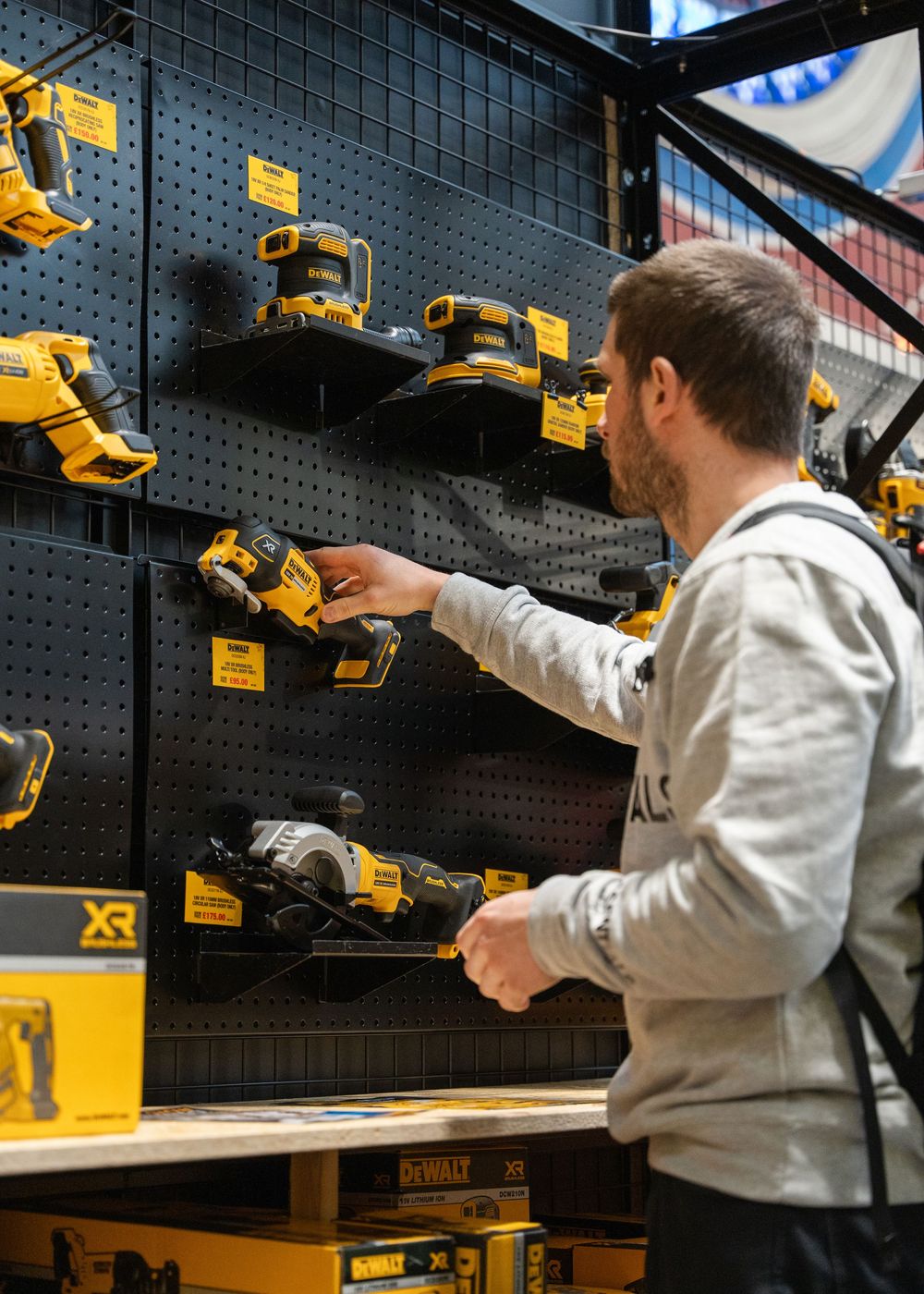 Power tools arranged on black pegboard display wall in retail setting.