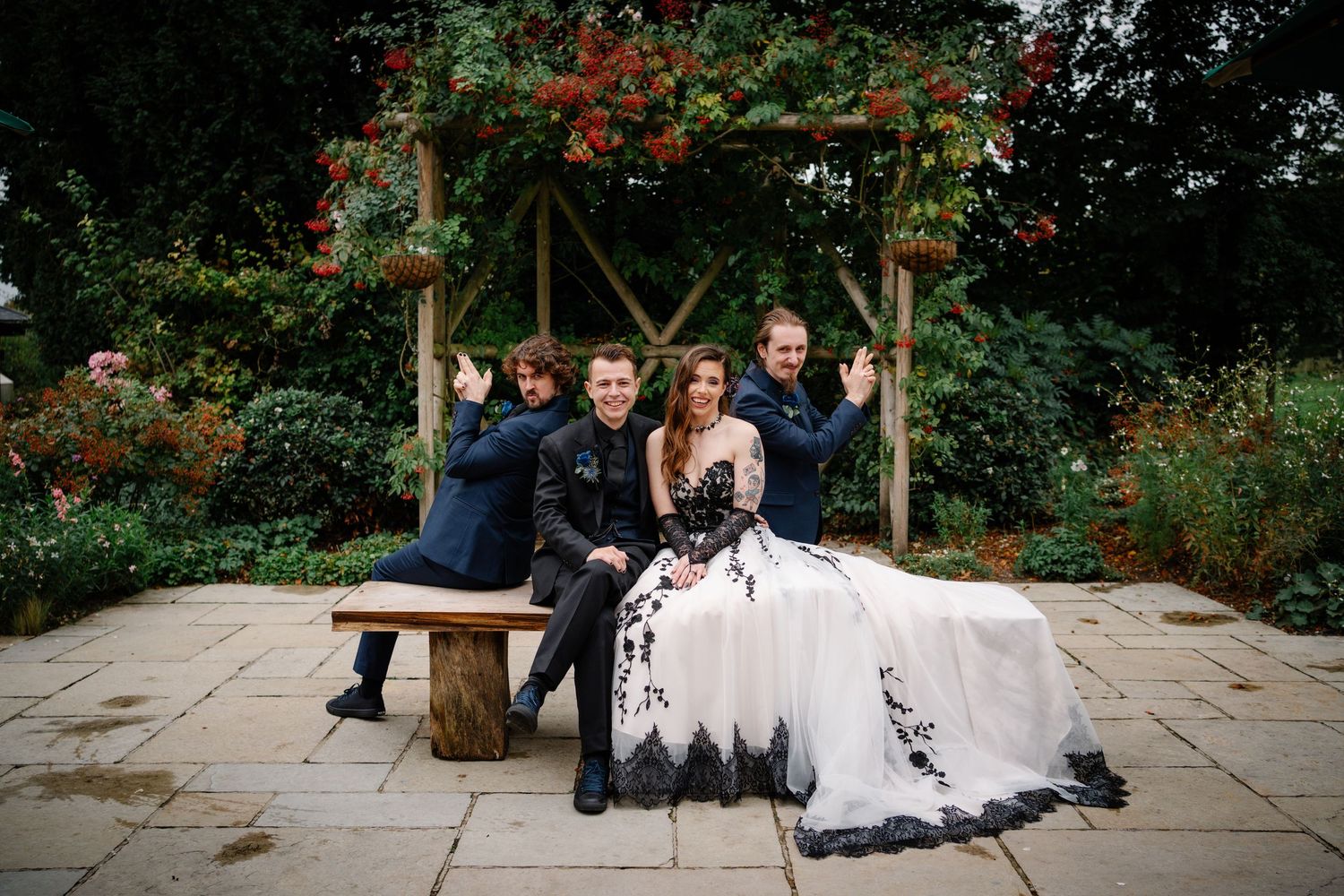 Alternative Couple at clock barn wedding venue playing photo roulette together with groomsmen posing for a fun group photo