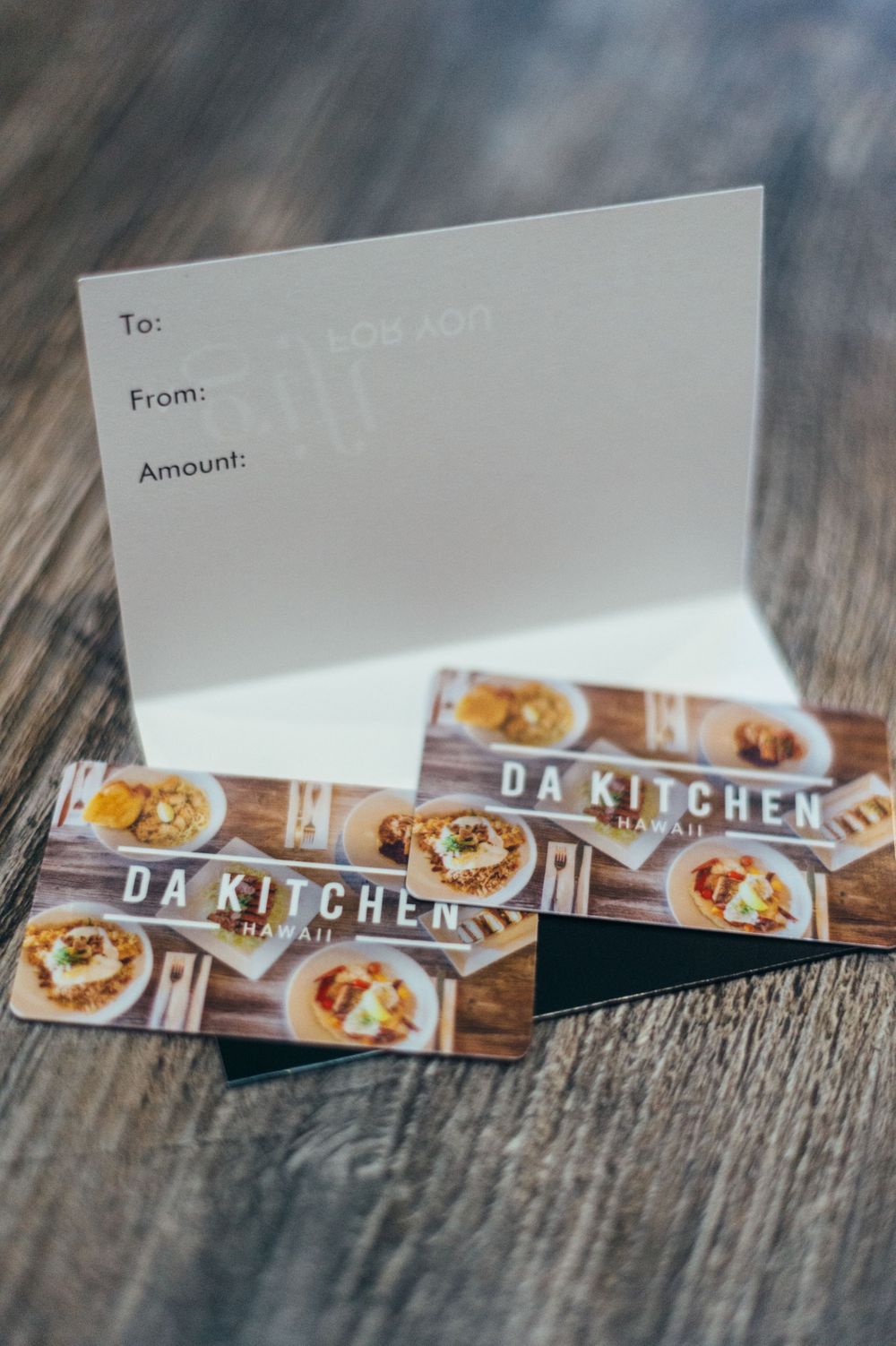 Gift card display for Da Kitchen restaurant on wooden surface.