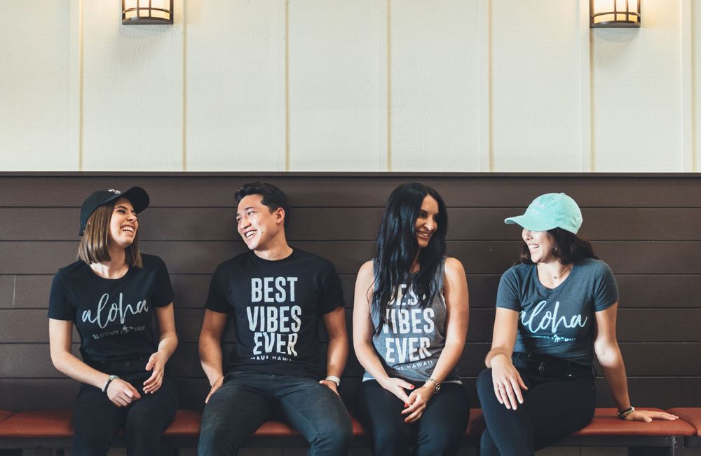 Group of staff members wearing black t-shirts seated against a wall.