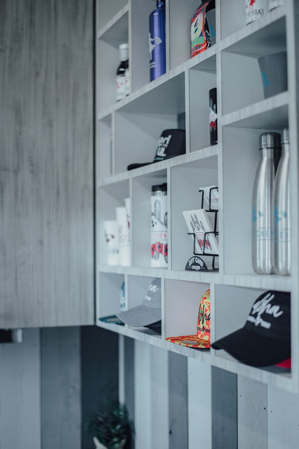 White shelving unit displaying various bottles and products against a gray wall.