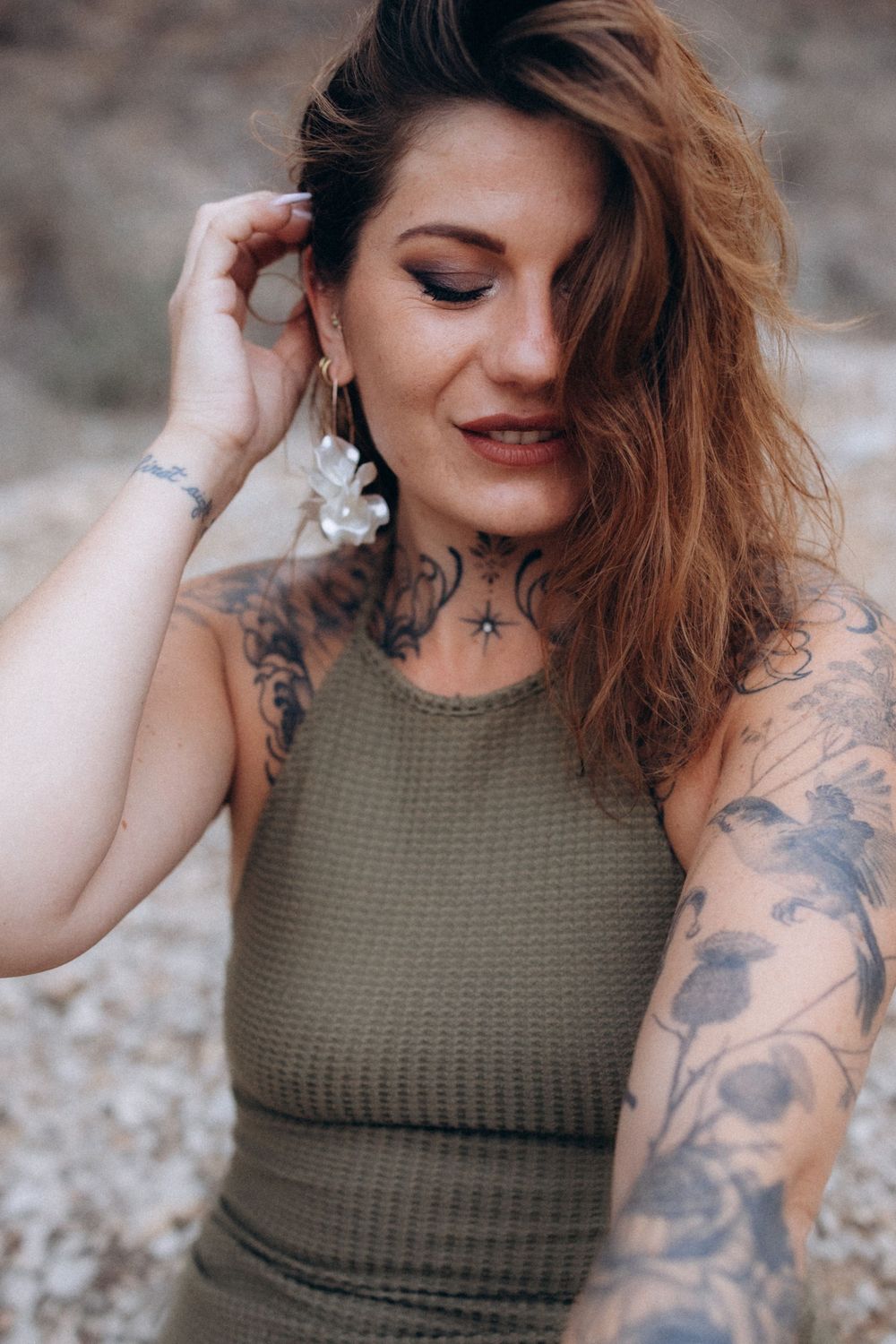 Woman in olive green tank top with arm tattoos poses outdoors in a series of casual portrait shots.