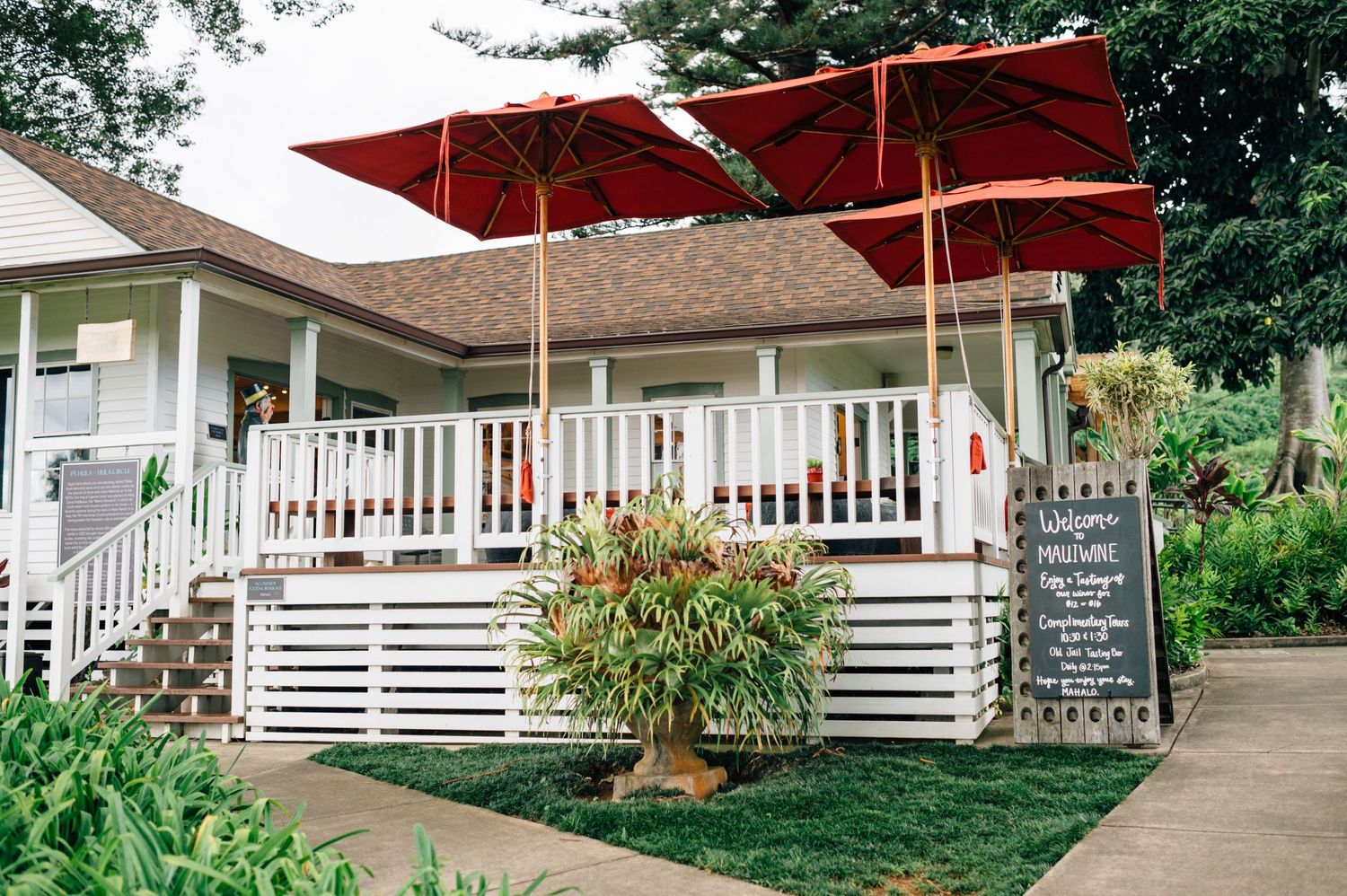 White plantation-style building with covered porch and red umbrellas along the walkway.