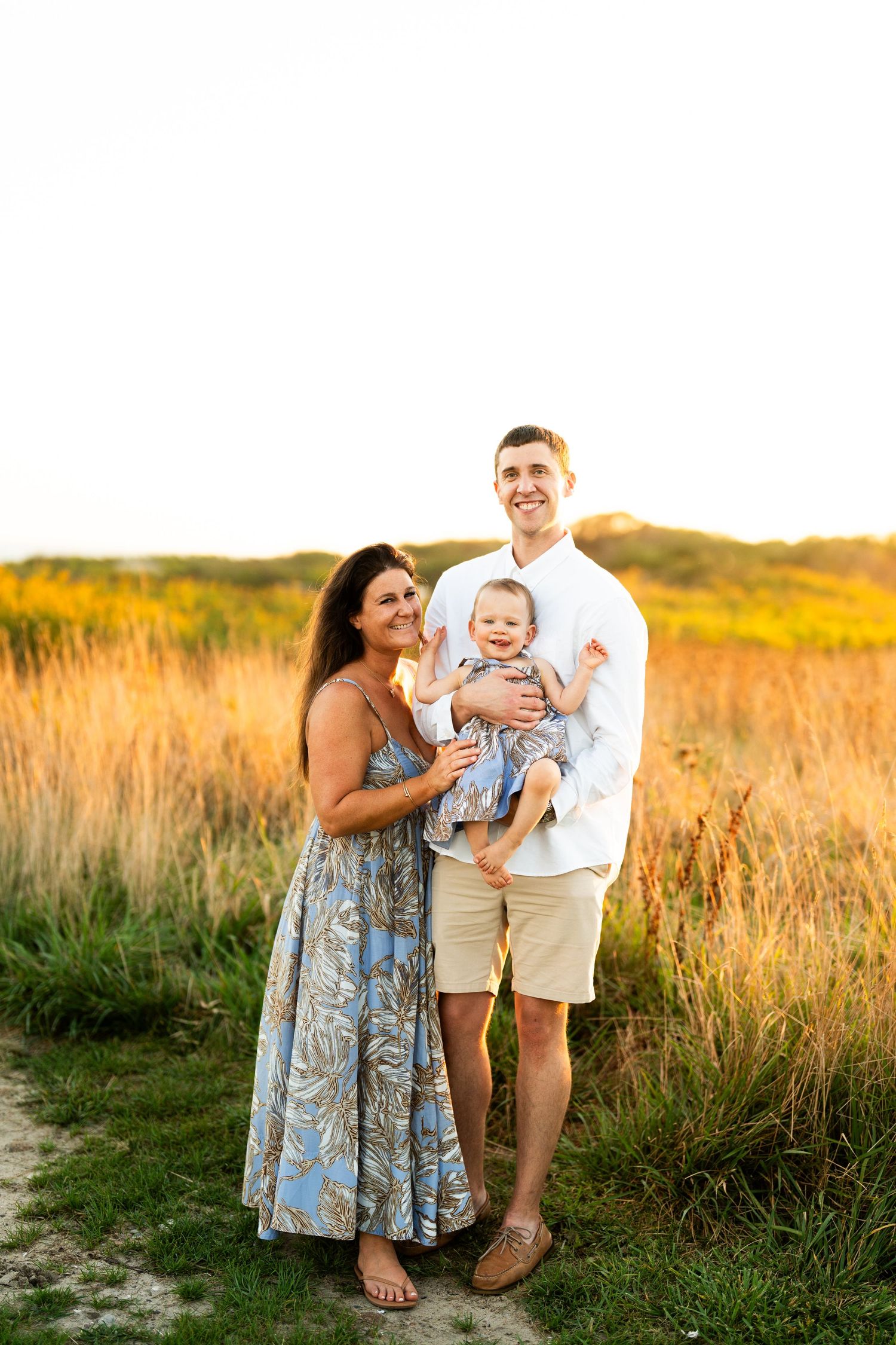 A family poses together in a golden field during sunset.