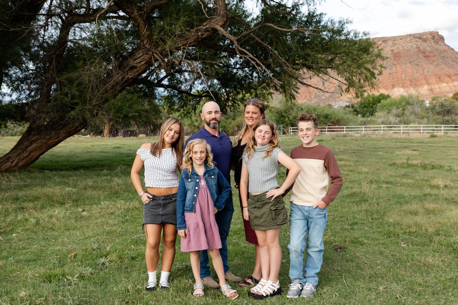 St. George family photographer captures family of 6 smiling at the camera in a Kirkland fields utah