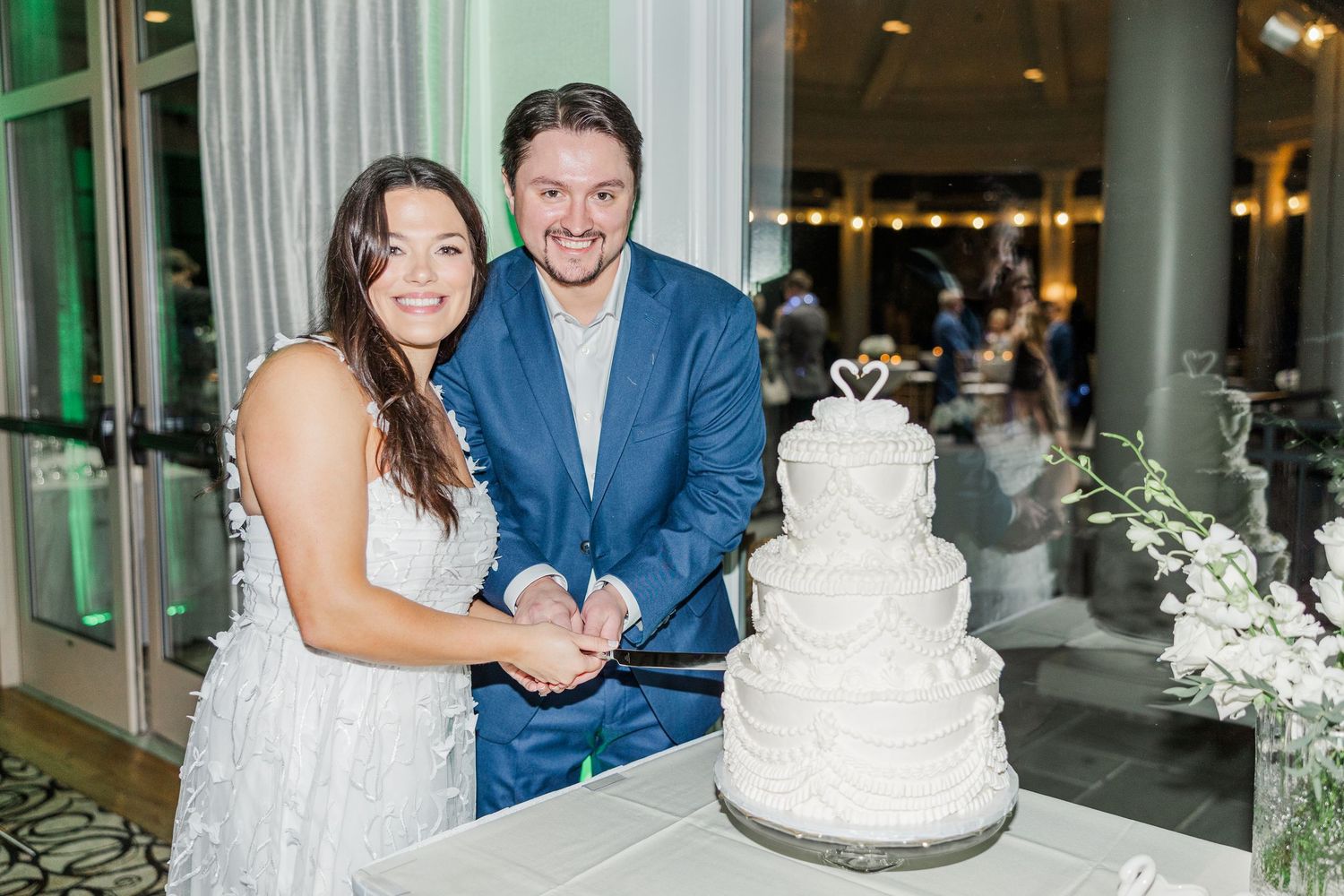 A wedding celebration collage showing elegant white floral decor, a tiered white cake, and formal attire at an indoor venue.
