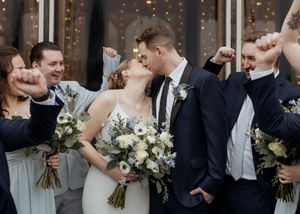bride and groom kiss while wedding party cheers behind them in exciting wedding celebration at Spruce and Iron, Moncton Golf Club wedding