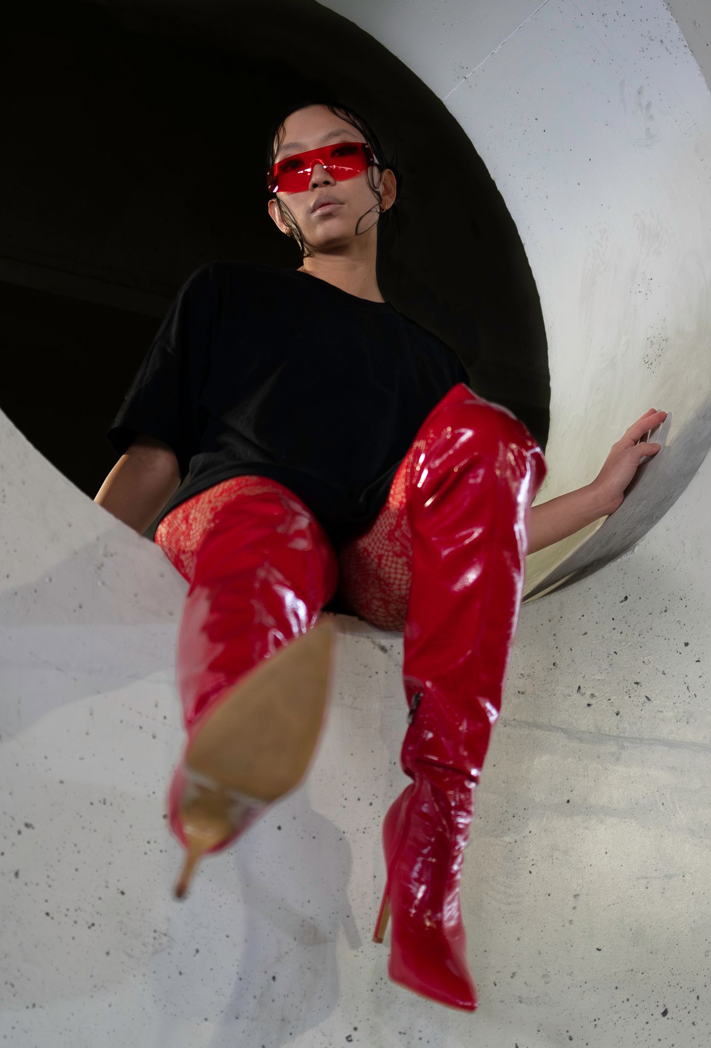 Person wearing black shorts and red boots performing movement sequence against white background.