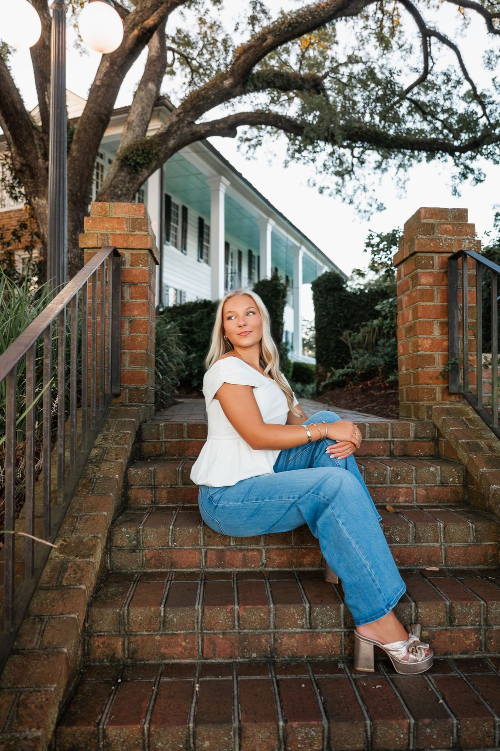 Casual portrait session on brick steps with large oak trees in background.
