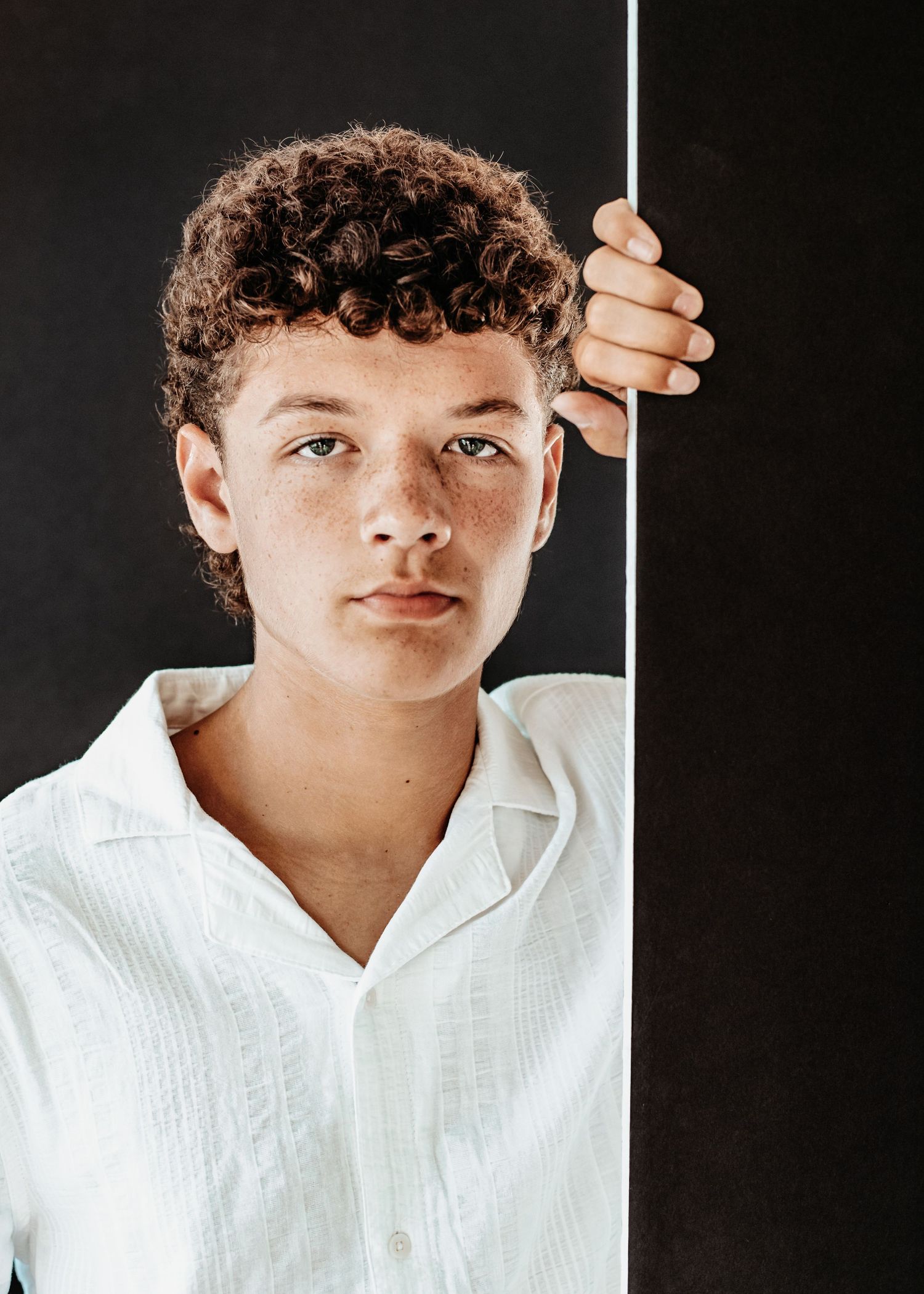 A person in a white collared shirt poses against a dark background in a series of similar headshots.