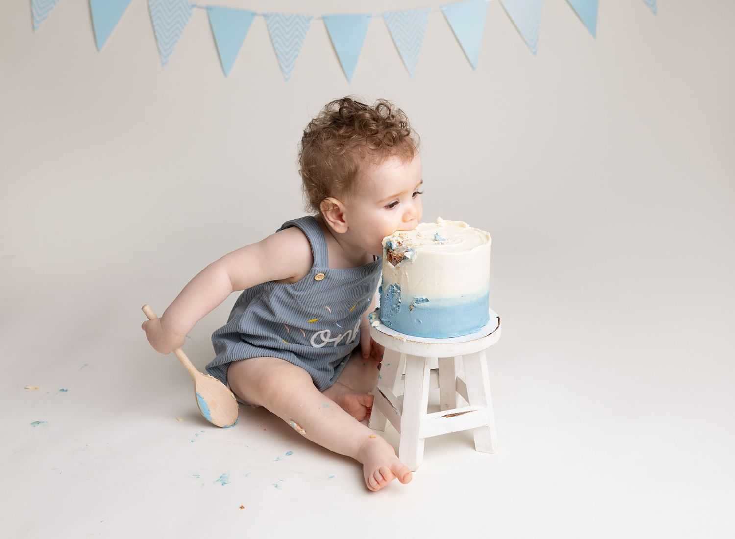 Baby boy eats blue and white cake, face first during his blue themed simple cake smash session in Renfrew studio
