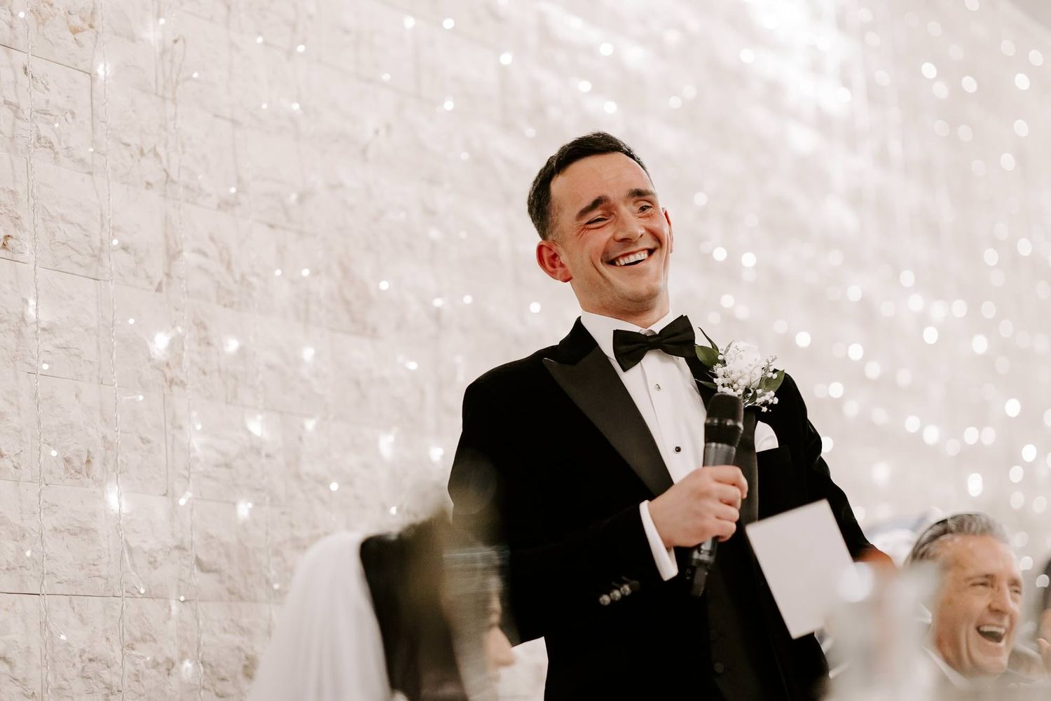 A black and white wedding photo collage showing candid moments of laughter and joy between people at a celebration.