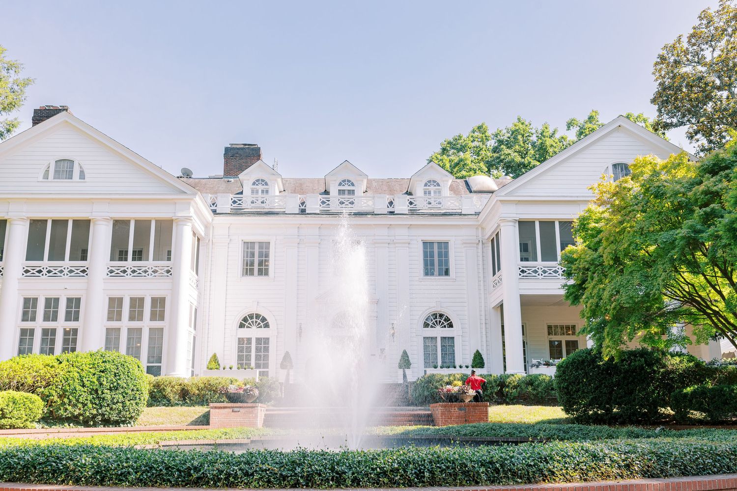 White colonial-style house with pillars and landscaping features multiple exterior views in a panoramic collage.