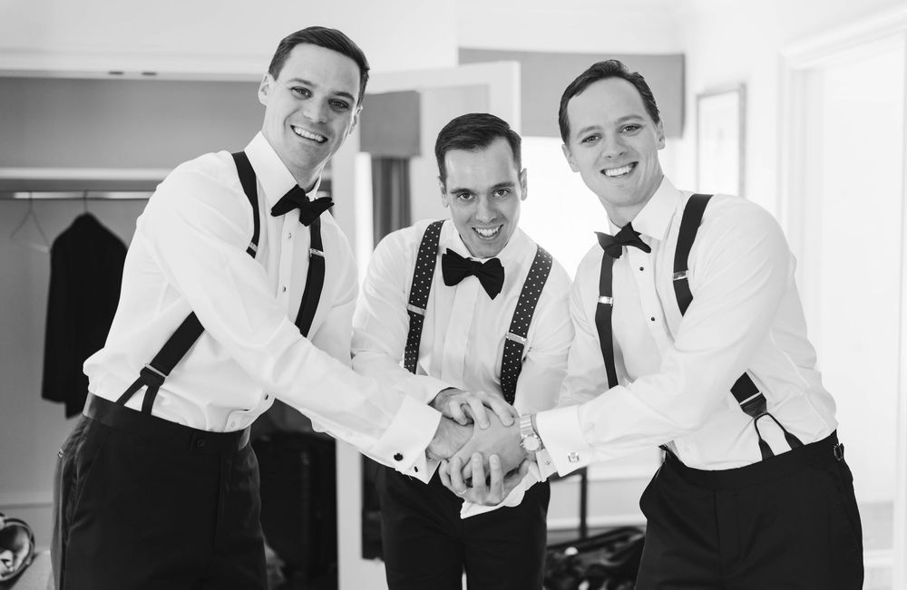 Groomsmen in white shirts and suspenders getting ready before wedding ceremony. Appleford Estate. Villanova, PA.