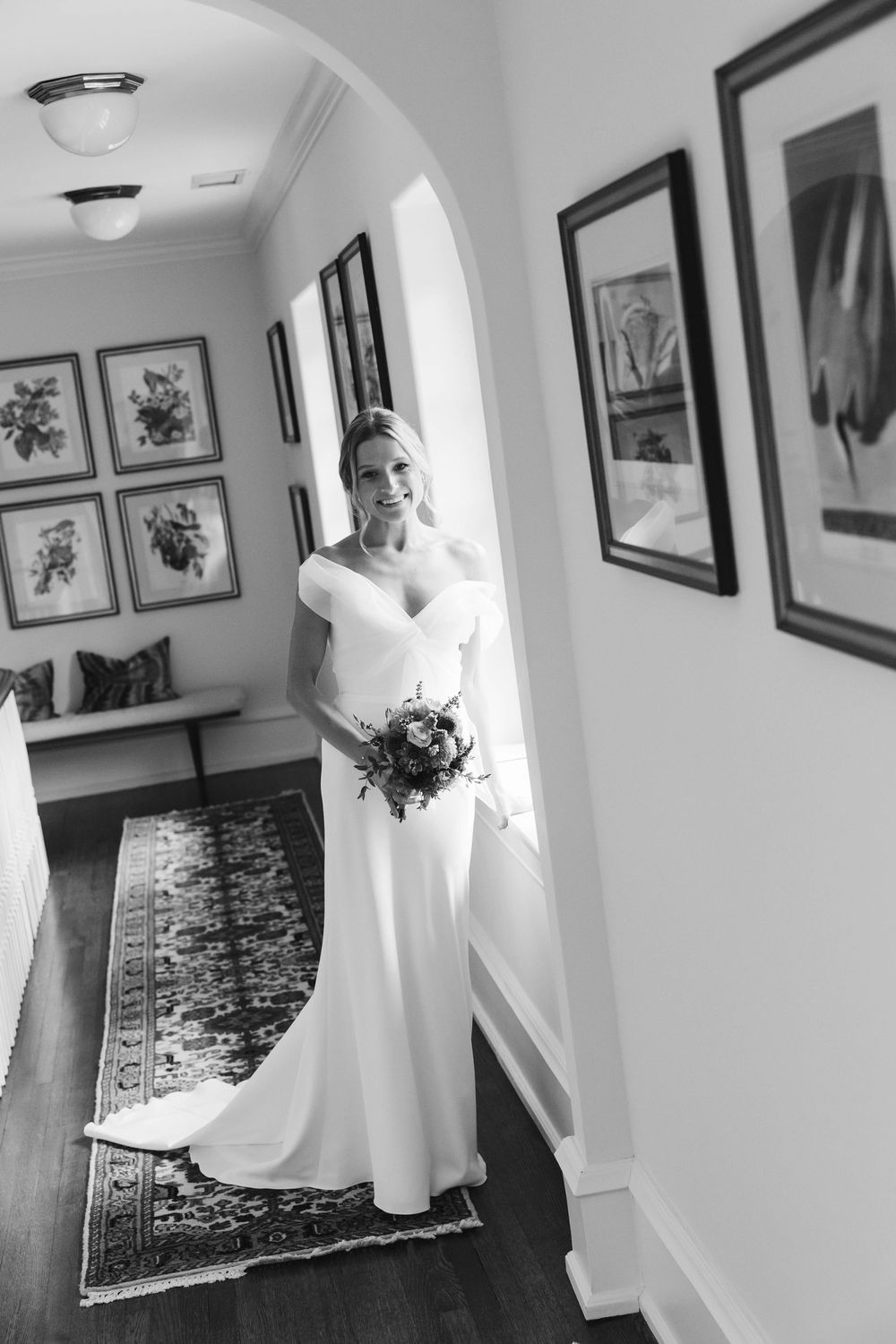 Elegant bridal portrait in hallway with black and white framed artwork. Appleford Estate. Villanova, PA.