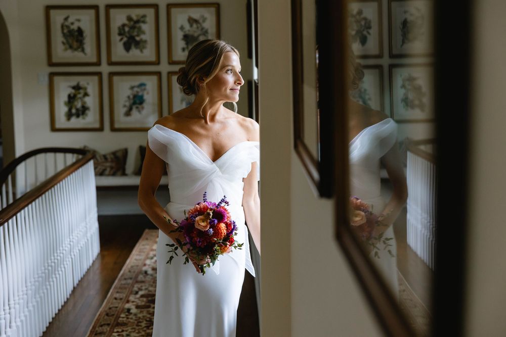 Classic bridal portrait in white dress against hallway with decorative wall art. Appleford Estate. Villanova, PA.
