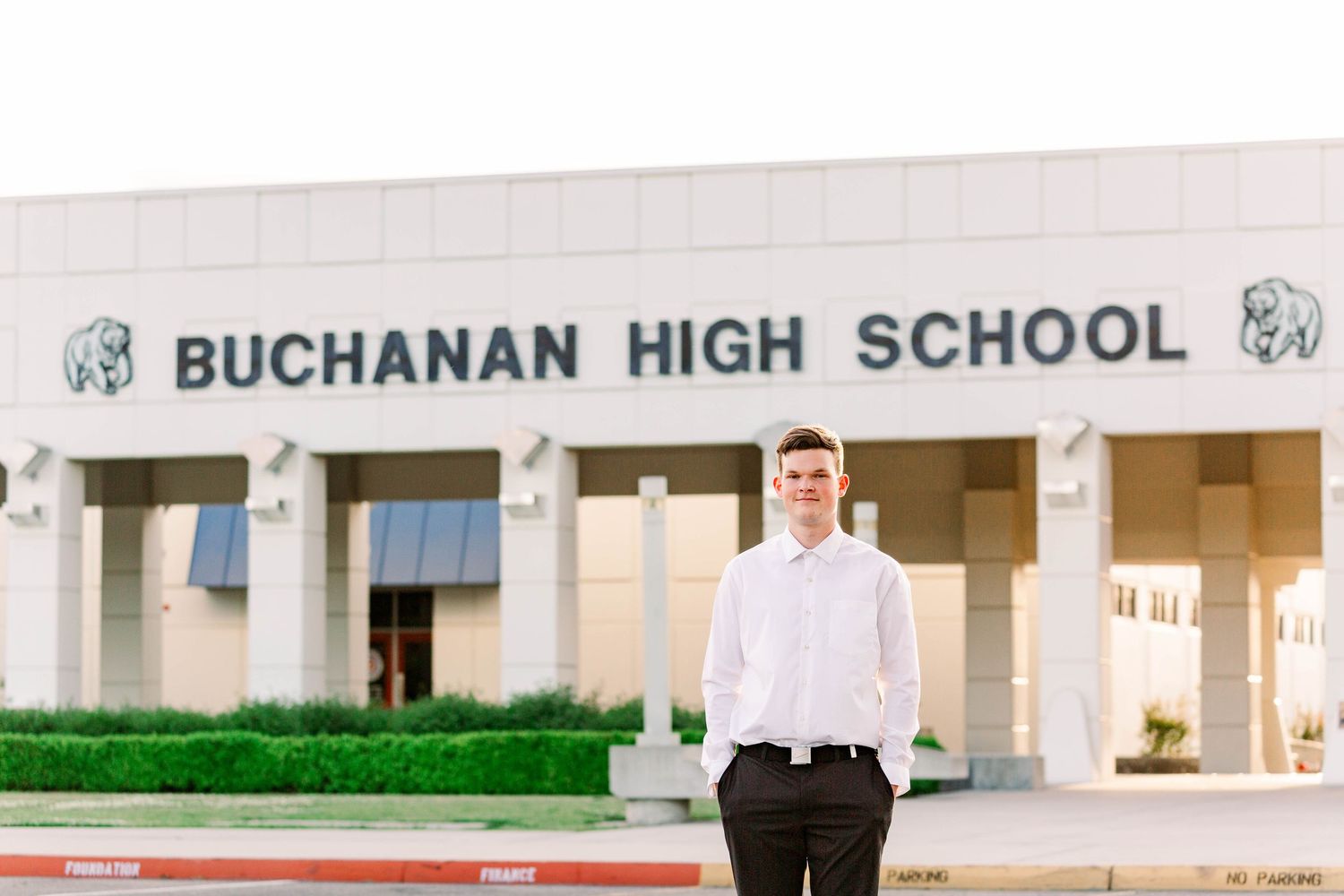 A student stands in front of Buchanan High School's entrance on a sunny day.