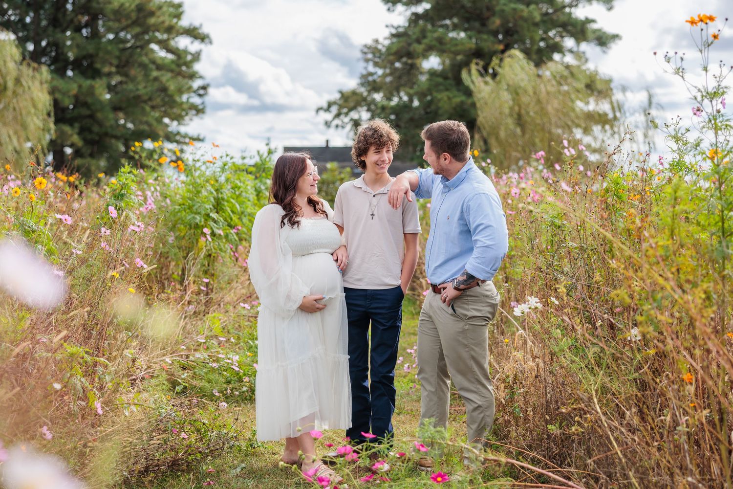 A couple walks through a wildflower meadow on a sunny autumn day during an outdoor photo session.