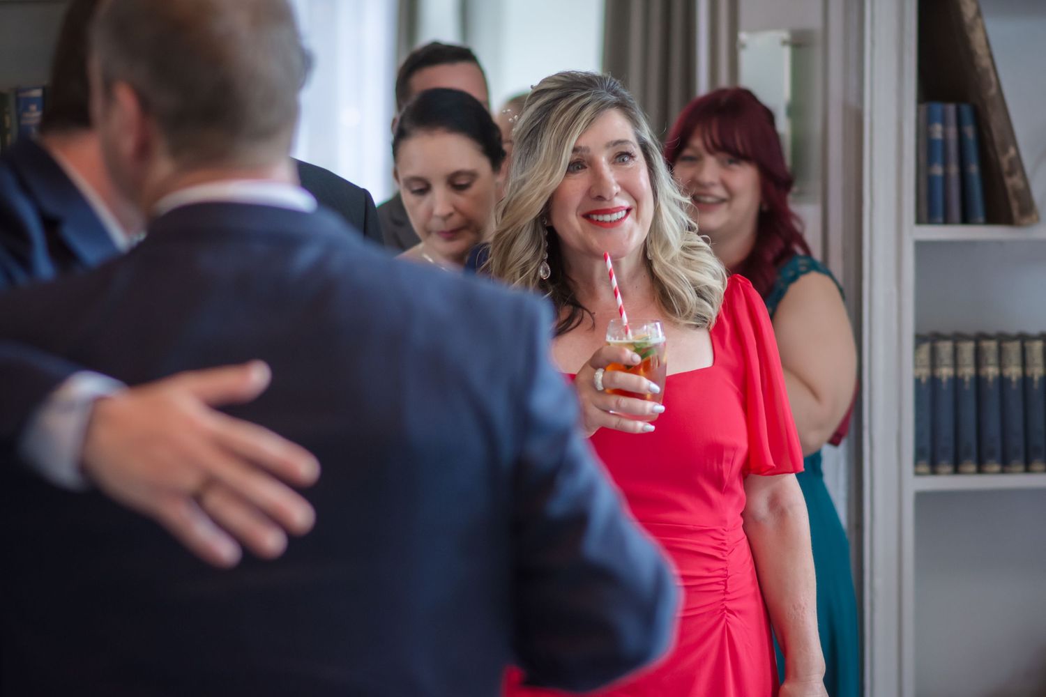 Wedding guests in formal attire share laughter and embraces during a wedding celebration at DeVere Cranage Estate in Holmes Chapel, Cheshire