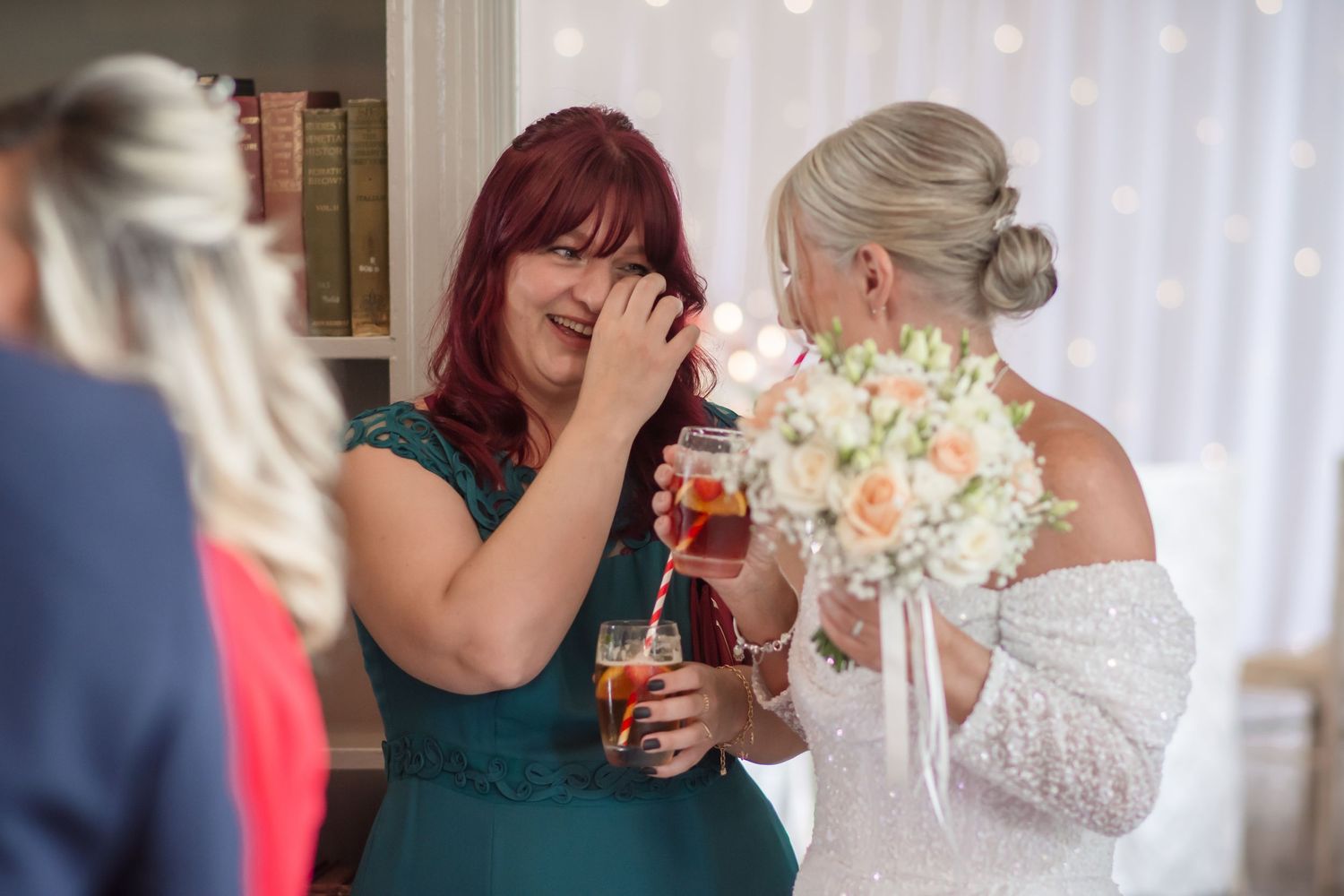 Two people clink glasses together in celebration at a formal event with white curtains in the background.