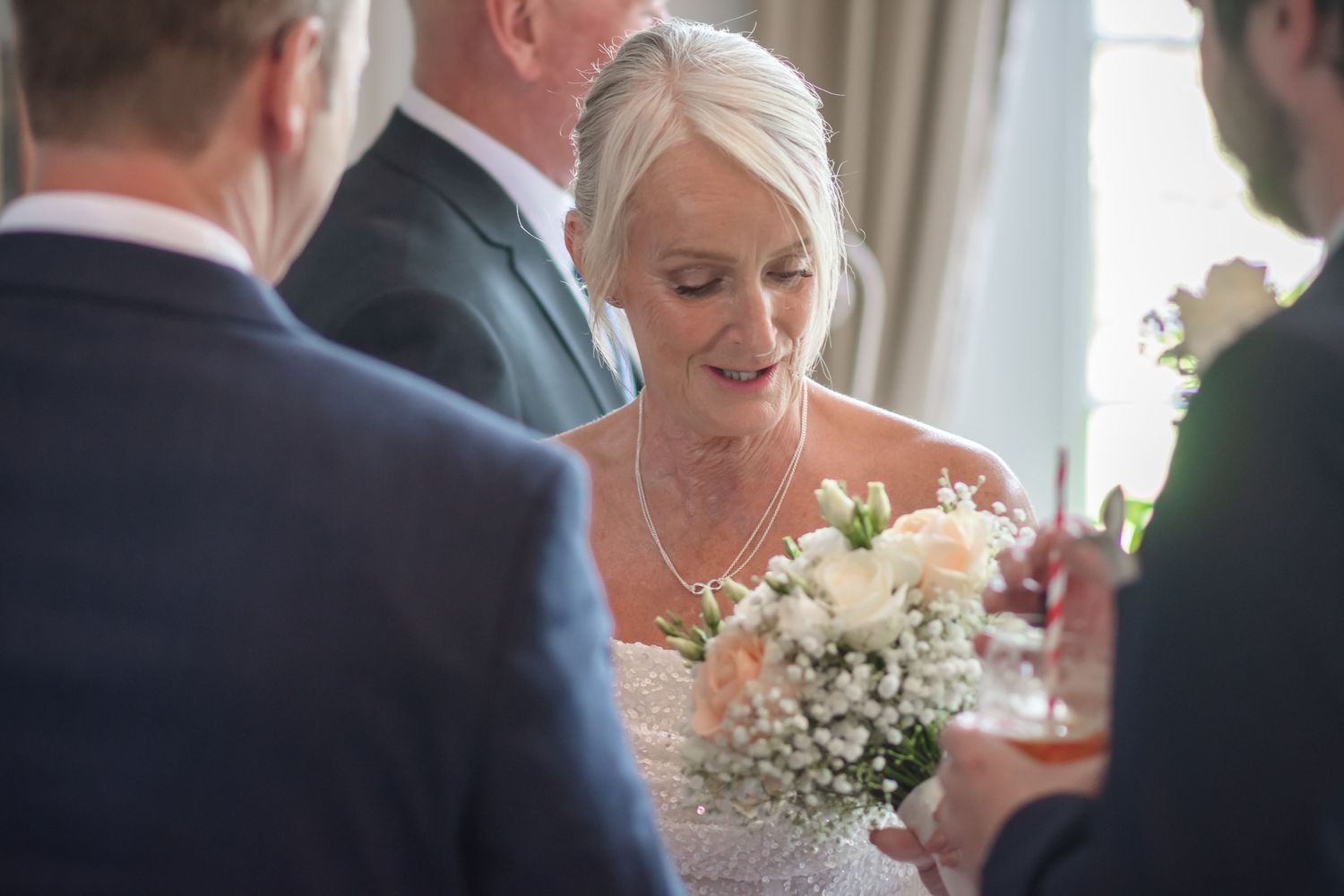 A bride and groom share an intimate moment during their wedding reception while surrounded by guests.