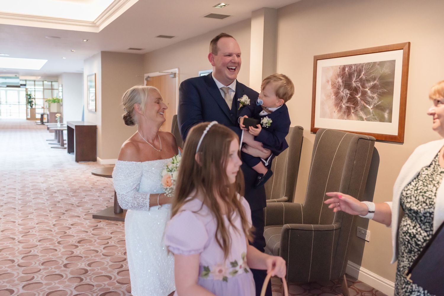 Wedding guests gathering in the elegant gallery hallway at De Vere Cranage Estate; indoor wedding photography in Cheshire by Michael Pardoe