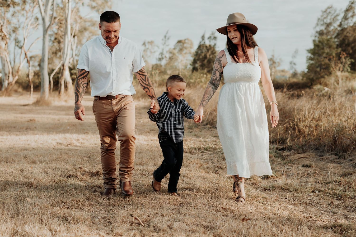 Family in casual attire poses together during golden hour in a Gladstone rustic outdoor setting.